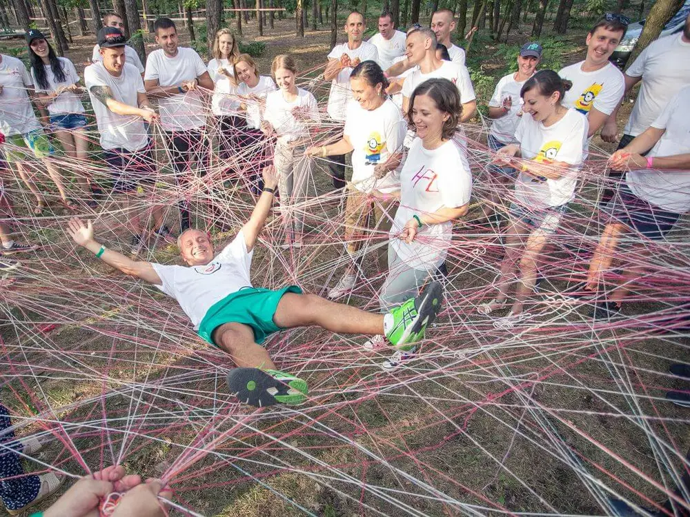 Equipo de empresa sosteniendo a un compañero sobre una red de cuerdas