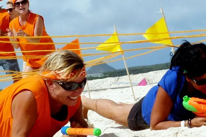 Equipos de empresa en una prueba de equilibrio en la playa